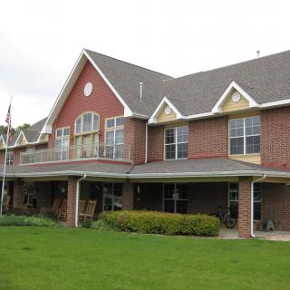 A large two-story brick house with a well-maintained lawn and garden.