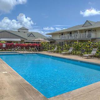 A sunny day at a resort with a large swimming pool surrounded by buildings and deck chairs.