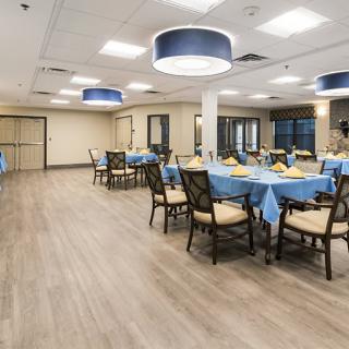 A spacious dining area with tables covered in blue tablecloths and comfortable seating.