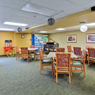 A community room with tables and chairs, featuring a popcorn machine and decorative elements.