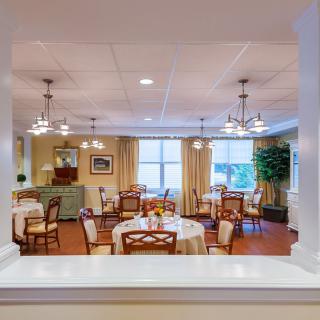 An elegant dining room setup with round tables, chairs, and chandeliers.