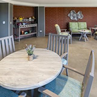 A modern lounge area featuring a wooden table with chairs and additional seating in the background.