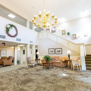A spacious and elegantly decorated lobby with a large chandelier, seating area, and staircase.