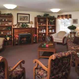 A cozy living room with armchairs, a sofa, bookshelves, and a fireplace.