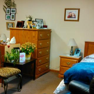 A cozy bedroom with wooden furniture, including a dresser, nightstand, and bed.