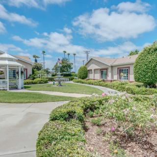 A scenic view of a landscaped garden with a gazebo and neatly trimmed hedges under a blue sky.