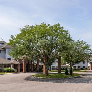A view of a residential building surrounded by trees with a clear sky.