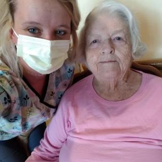 A caregiver smiling with an elderly woman, both enjoying a moment together.