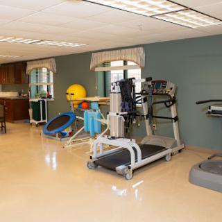A well-equipped gym area featuring various exercise machines and rehabilitation tools.
