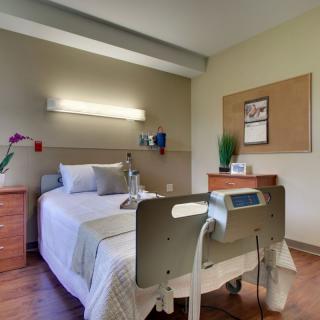 A tidy hospital room with a bed and medical equipment.