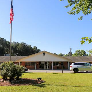 A clear day outside a building with an American flag and a parked vehicle.