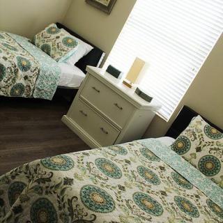 A cozy bedroom with twin beds featuring patterned bedding and a shared dresser with a lamp.