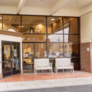 The entrance of a building featuring glass windows and benches outside.