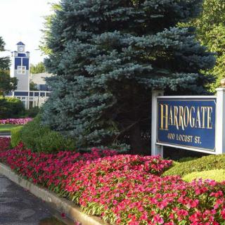 Entrance to a residential complex with colorful flowers and a prominent sign.