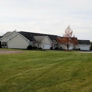 A peaceful suburban setting with well-maintained houses and an open grassy area.
