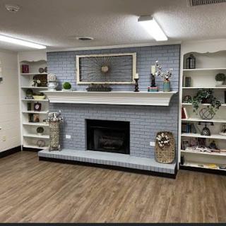 A cozy living room with a blue brick fireplace and built-in shelves.