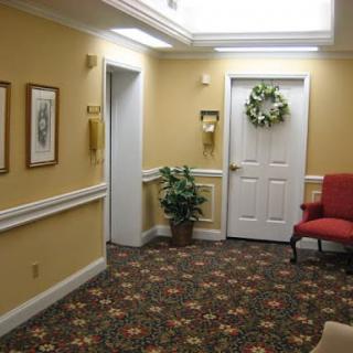 A cozy interior hallway with a carpet, red chair, plant, and decorated door.