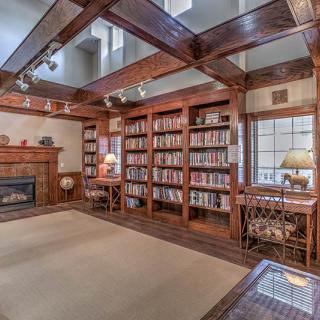 A cozy library with wooden bookshelves and a fireplace, perfect for reading.