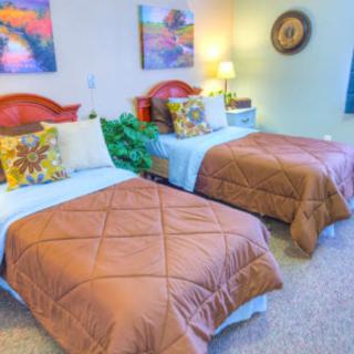 A cozy bedroom with twin beds, adorned with decorative pillows and warm lighting.