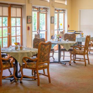 A cozy dining area with neatly arranged tables and chairs near large windows.