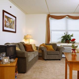A cozy living room with a sofa, armchair, and a TV.