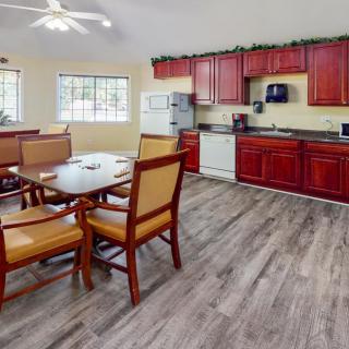 A modern kitchen with red cabinets and a dining area featuring wooden flooring and a ceiling fan.