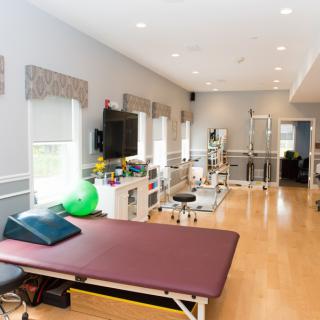 A well-equipped physical therapy clinic featuring treatment tables and exercise equipment.