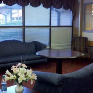 A cozy living room with blue sofas and a round wooden table, adorned with a vase of flowers.
