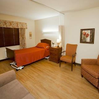A cozy and well-furnished bedroom featuring a single bed, chairs, and warm lighting.