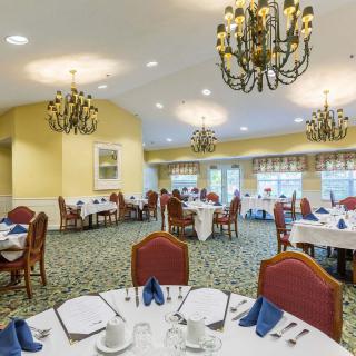 An elegant dining room with chandeliers and neatly arranged tables ready for guests.