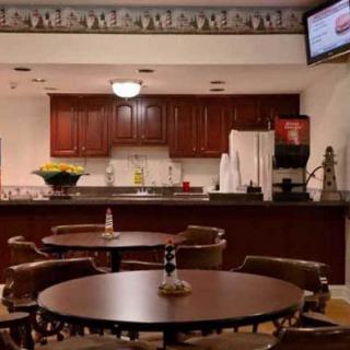 A cozy cafe with round tables, chairs, and a kitchen counter in the background.