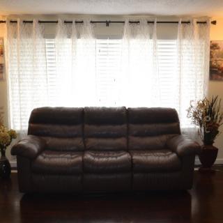 A cozy living room with a brown sofa in front of a window adorned with sheer curtains.