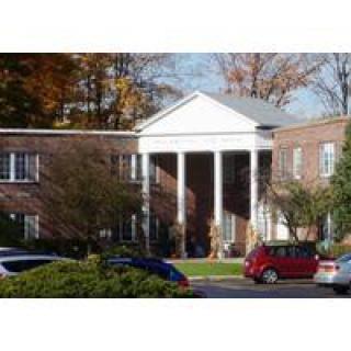 A building with classical columns and parked cars in front.