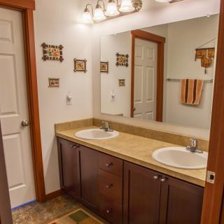 A spacious bathroom featuring a double sink vanity with a large mirror and elegant lighting.