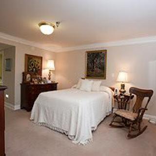 A cozy bedroom with a neatly made bed, side table lamps, and a rocking chair.