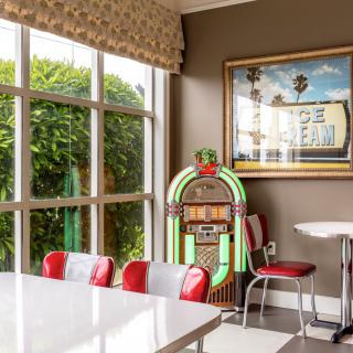 A retro diner interior featuring a classic jukebox and red seating by a large window.