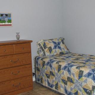 A minimalist bedroom with a single bed and wooden dresser.