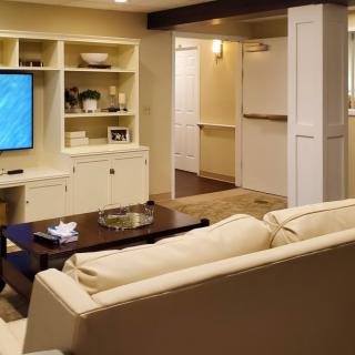 A cozy living room with a television, comfortable seating, and built-in shelves.