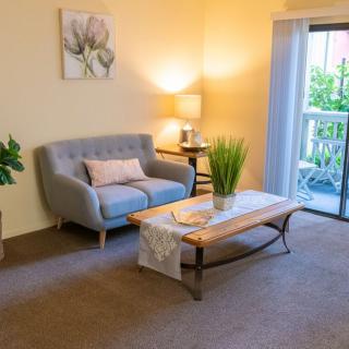 A cozy living room with a sofa, coffee table, and a decorative plant, illuminated by warm lighting.