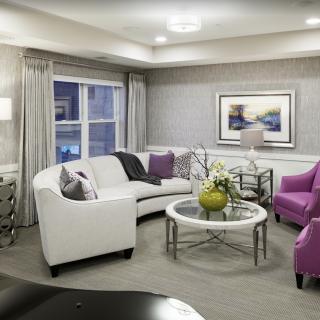 A modern living room featuring a white sofa, purple chairs, and a stylish coffee table with elegant decor.