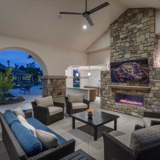 A modern outdoor patio with comfortable seating and a stone fireplace, creating a cozy evening ambiance.