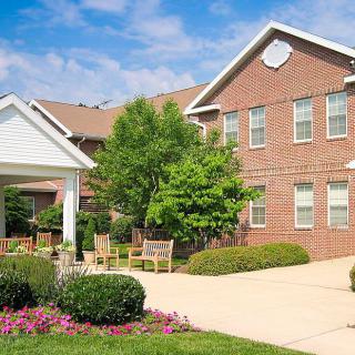 A well-maintained brick building with a landscaped garden and outdoor seating area.