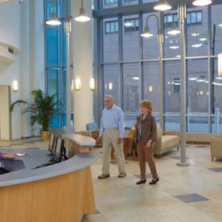 People standing in a modern lobby with comfortable seating and large windows.