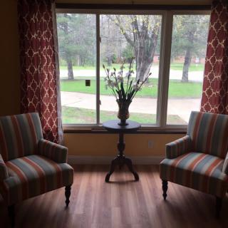 A cozy sitting area with striped chairs and a small table by the window.