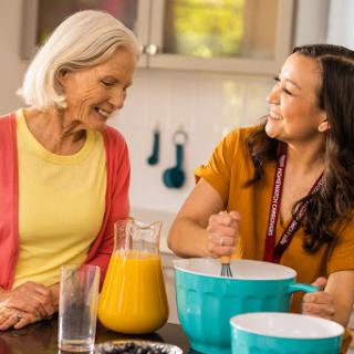 A joyful moment in the kitchen as a grandmother and granddaughter bond over cooking.