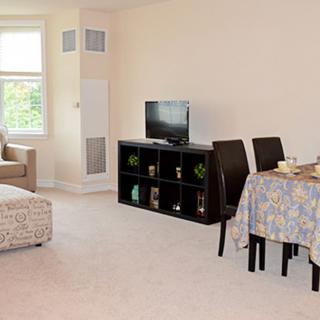 A cozy living and dining area with a sofa, TV, and table set.