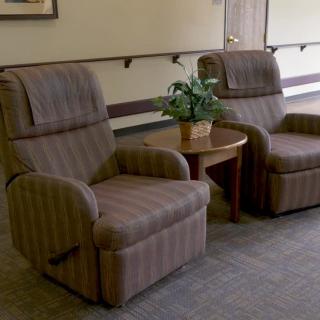 A cozy waiting area with two armchairs and a small table with a plant.