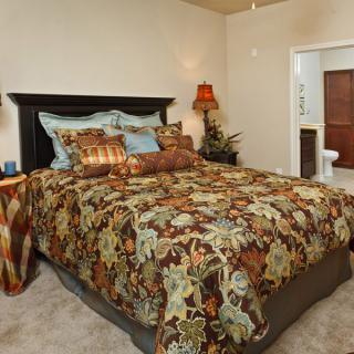 A cozy bedroom with a floral-patterned bedspread and decorative pillows.