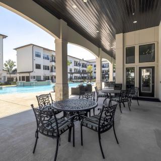 Outdoor patio area with seating overlooking a pool at an apartment complex.