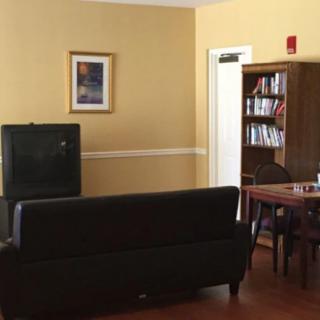 A cozy living room setup with a sofa facing a television, a bookshelf filled with books, and a small table nearby.